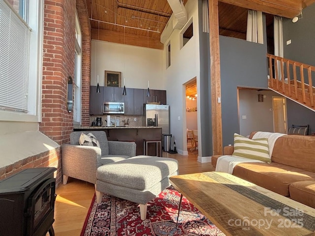 living room with a wood stove, high vaulted ceiling, wooden ceiling, and beam ceiling