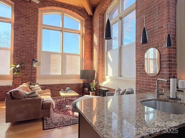 living room featuring beam ceiling, sink, wooden ceiling, a towering ceiling, and light wood-type flooring