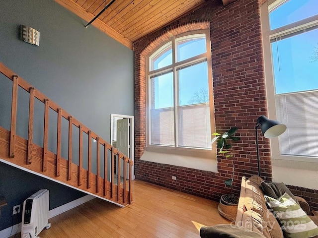 interior space with wooden ceiling, high vaulted ceiling, radiator, light wood-type flooring, and brick wall