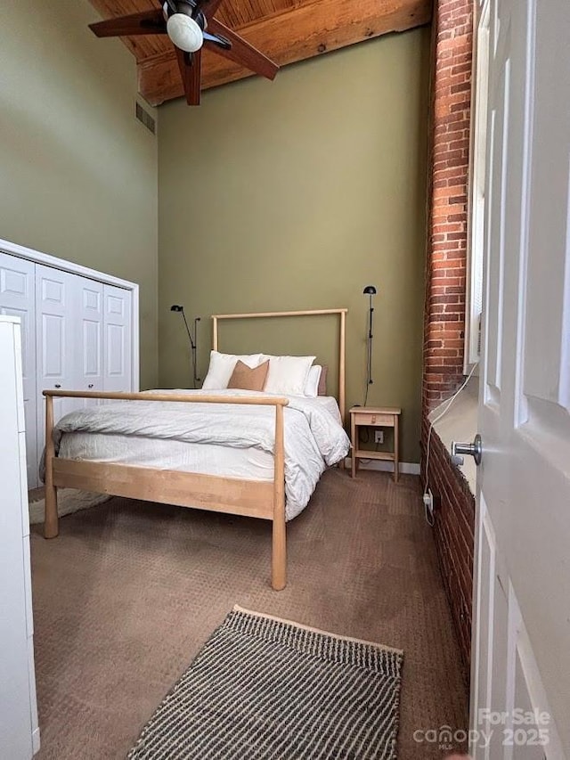 carpeted bedroom with beamed ceiling, a towering ceiling, ceiling fan, and wooden ceiling