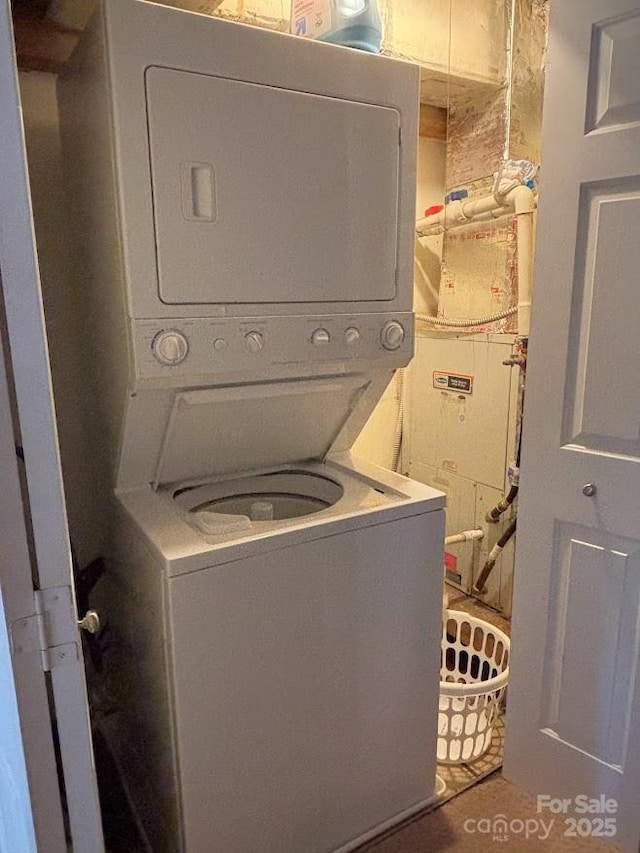 clothes washing area with dark tile patterned floors and stacked washer / dryer