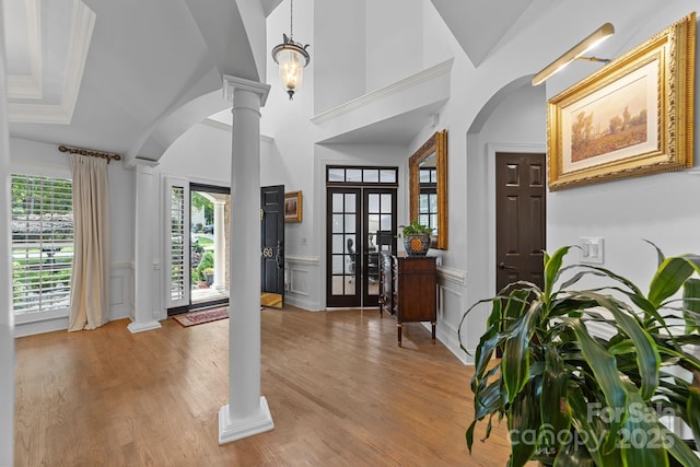 entryway with light wood-type flooring, french doors, a high ceiling, and decorative columns