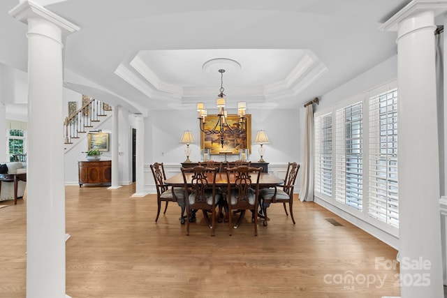 dining area featuring a chandelier, a tray ceiling, decorative columns, and crown molding