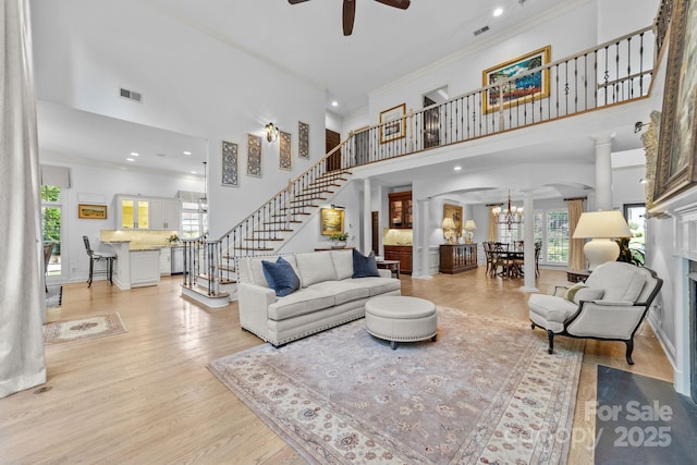 living room with a high ceiling, light hardwood / wood-style floors, ceiling fan, and crown molding