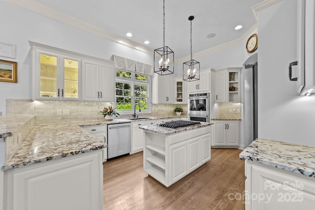 kitchen with sink, appliances with stainless steel finishes, decorative light fixtures, a kitchen island, and white cabinetry