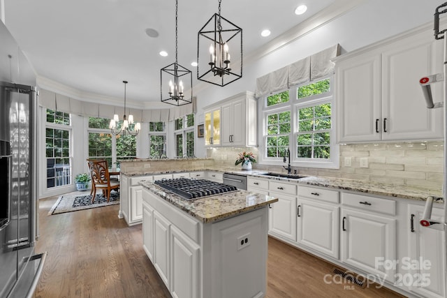 kitchen featuring white cabinets, a kitchen island, hanging light fixtures, and a wealth of natural light