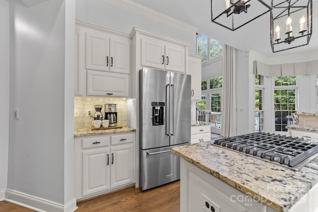 kitchen with stainless steel appliances, white cabinetry, and hanging light fixtures