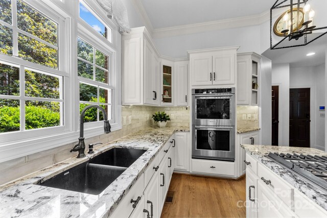 kitchen with white cabinets, sink, stainless steel appliances, and hanging light fixtures