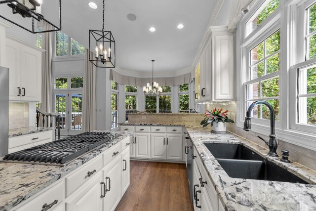 kitchen featuring sink, a notable chandelier, crown molding, stainless steel gas stovetop, and white cabinets