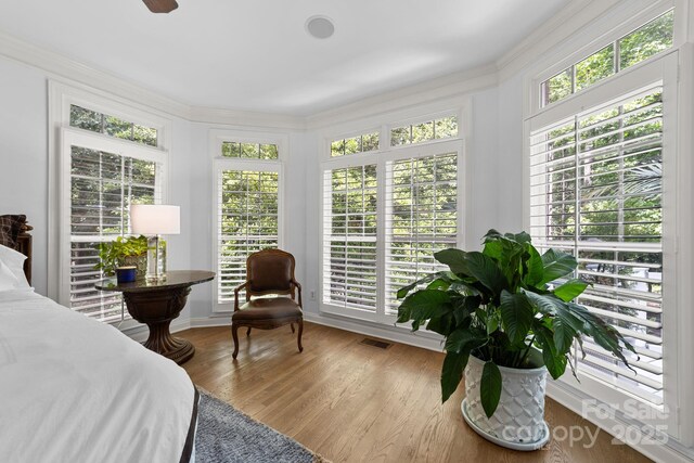 bedroom featuring multiple windows, crown molding, and light wood-type flooring