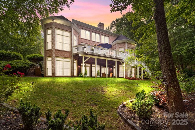 back house at dusk featuring a yard and a deck