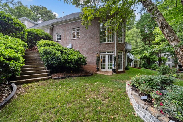 rear view of house featuring a lawn and french doors