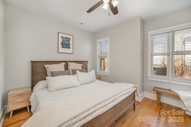 bedroom with ceiling fan, light hardwood / wood-style flooring, and multiple windows