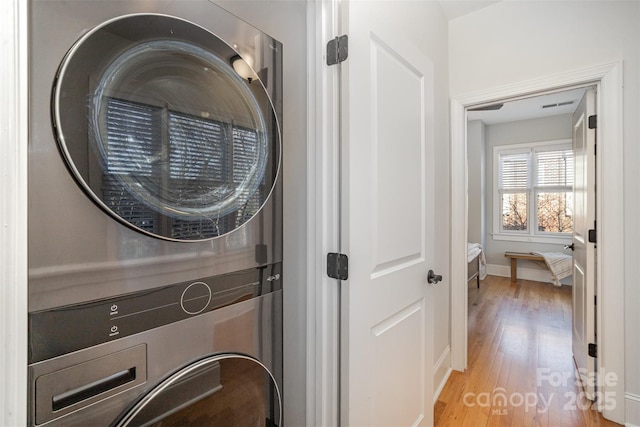 washroom featuring stacked washer and clothes dryer and hardwood / wood-style flooring