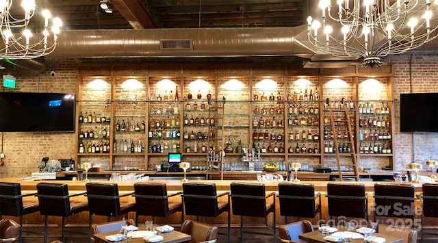 bar with brick wall, a chandelier, and beamed ceiling