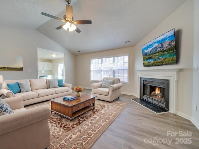 living room featuring hardwood / wood-style flooring, vaulted ceiling, plenty of natural light, and a textured ceiling