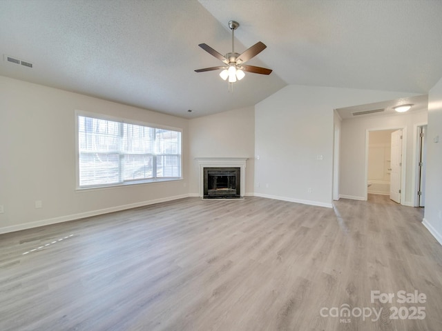 unfurnished living room with lofted ceiling, ceiling fan, light hardwood / wood-style flooring, and a textured ceiling