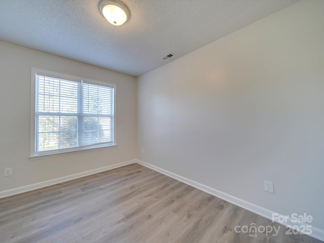 spare room featuring a textured ceiling and light wood-type flooring