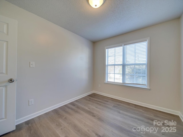 unfurnished room with a textured ceiling and light hardwood / wood-style flooring