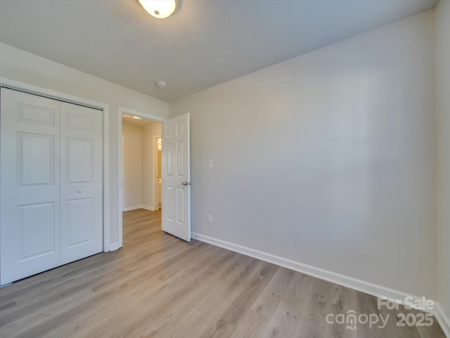 unfurnished bedroom with a closet, a textured ceiling, and light wood-type flooring