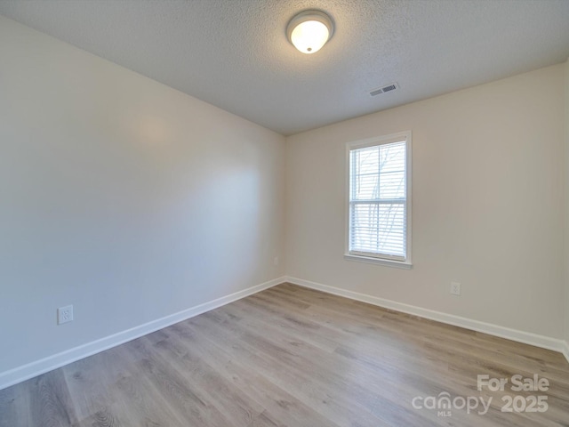 unfurnished room featuring a textured ceiling and light wood-type flooring