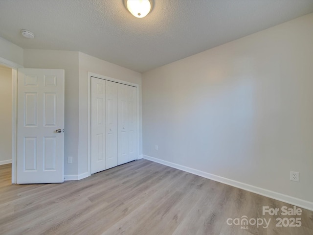 unfurnished bedroom featuring a closet, light hardwood / wood-style floors, and a textured ceiling