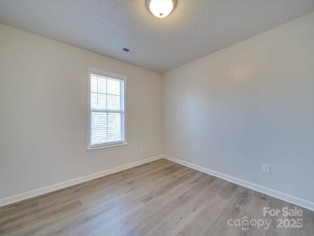 unfurnished room featuring light hardwood / wood-style floors and a textured ceiling