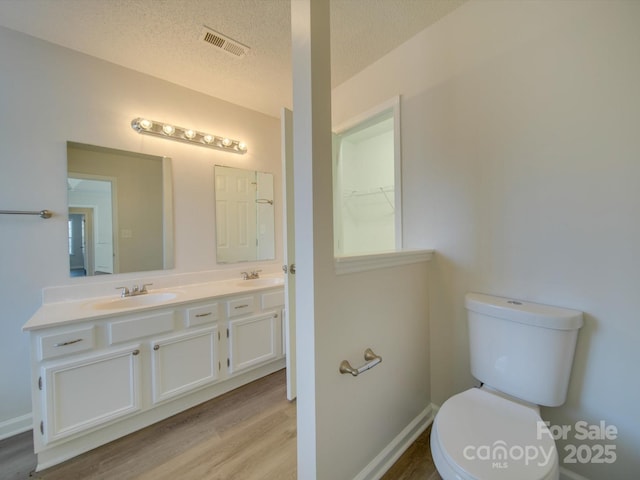 bathroom with vanity, wood-type flooring, a textured ceiling, and toilet