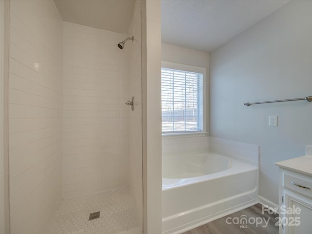 bathroom with hardwood / wood-style flooring, vanity, and plus walk in shower