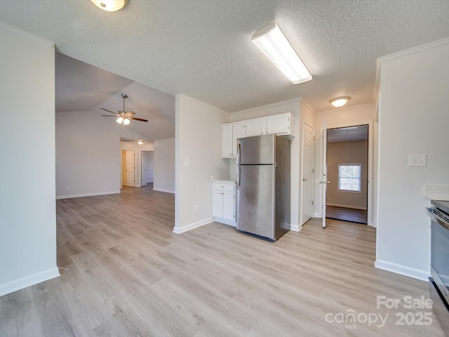 kitchen featuring stainless steel appliances, lofted ceiling, white cabinets, and light wood-type flooring