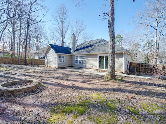 back of property featuring cooling unit, a patio area, and a fire pit