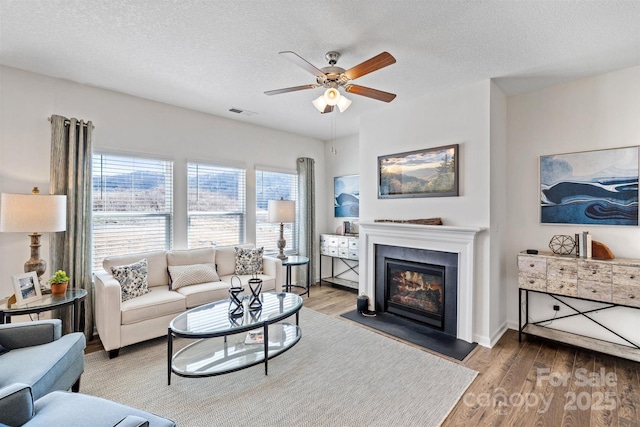 living room featuring ceiling fan, a textured ceiling, and hardwood / wood-style flooring