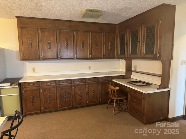 carpeted office space with built in desk and a textured ceiling