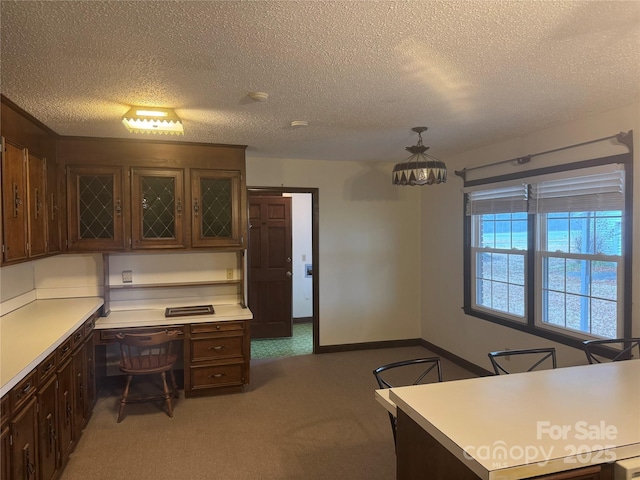 kitchen with dark brown cabinetry, hanging light fixtures, dark carpet, and a textured ceiling