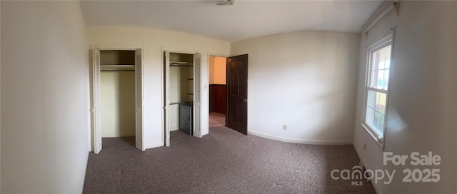 unfurnished bedroom featuring two closets and dark colored carpet