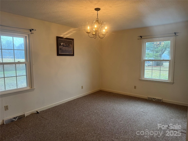 carpeted empty room with an inviting chandelier and a textured ceiling