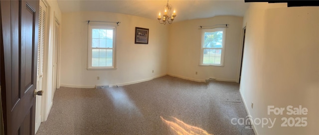 unfurnished room with a healthy amount of sunlight, carpet flooring, and a notable chandelier