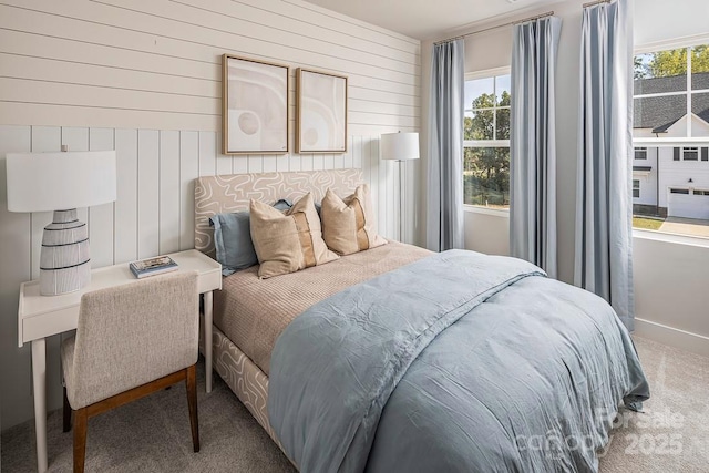 carpeted bedroom featuring wooden walls