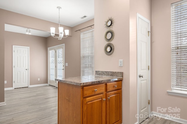 kitchen featuring kitchen peninsula, decorative light fixtures, light hardwood / wood-style floors, and a notable chandelier