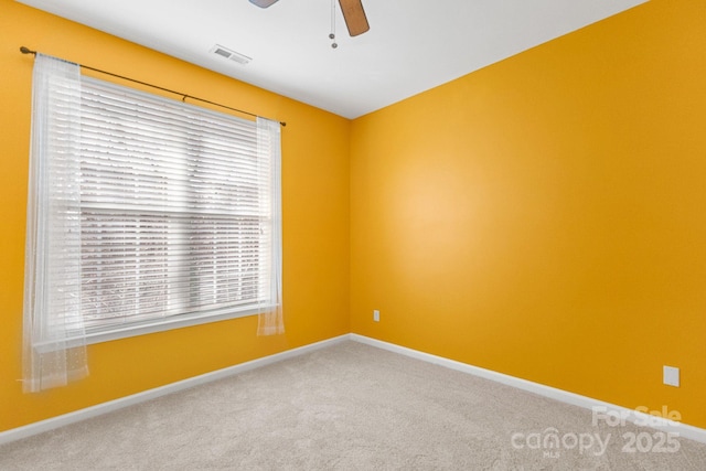 carpeted empty room with a wealth of natural light and ceiling fan