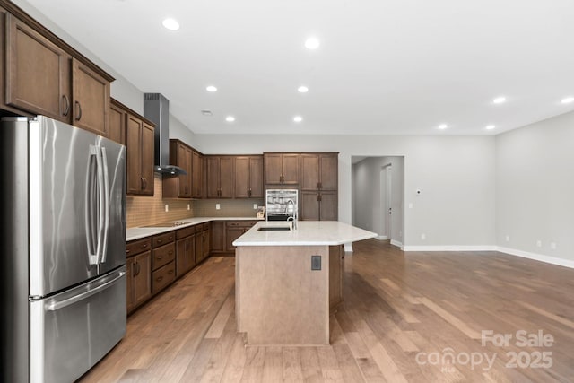253 Stone Mountain Way, Denver, NC 28037 - kitchen featuring freestanding refrigerator, wall chimney range hood, a sink, light countertops, and light wood-type flooring