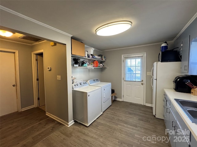 laundry room featuring sink, dark wood-type flooring, washer and dryer, and ornamental molding