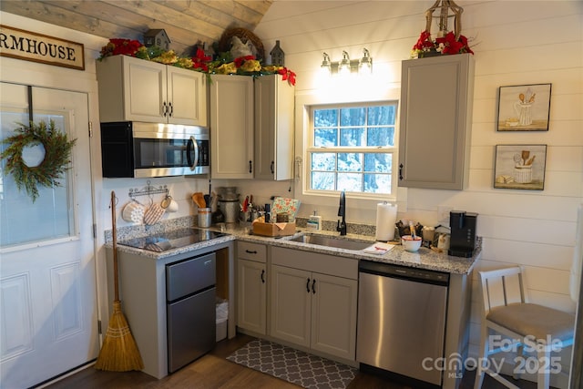 kitchen with dark hardwood / wood-style floors, gray cabinets, sink, appliances with stainless steel finishes, and light stone counters