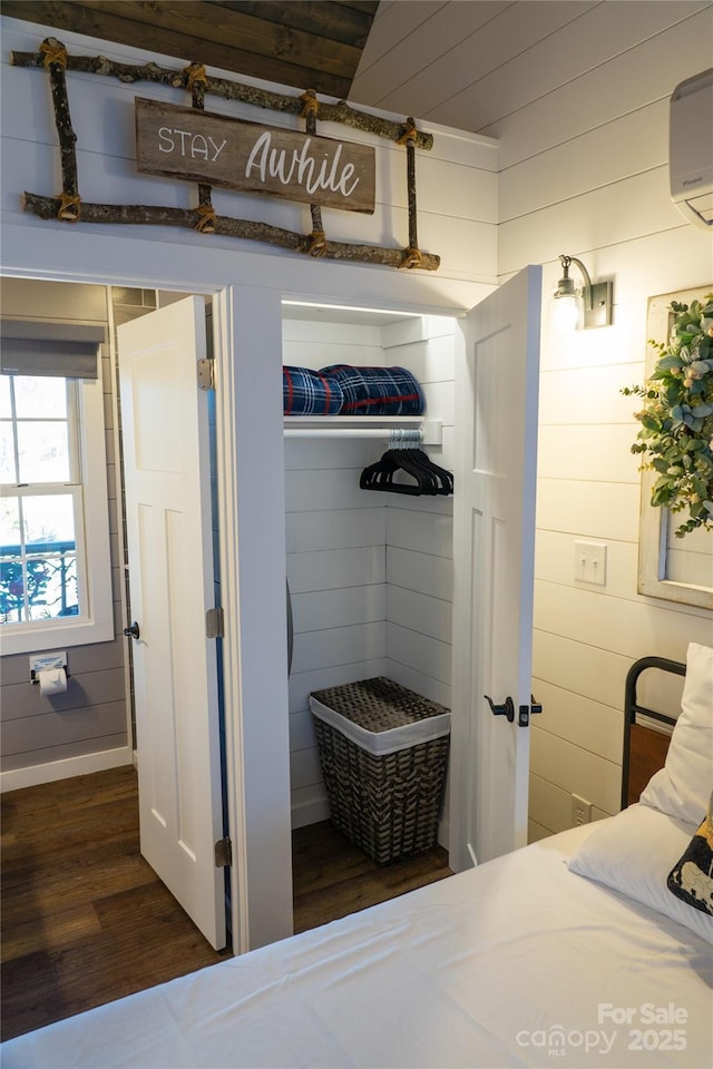 interior space featuring wood-type flooring, a wall unit AC, and wooden walls