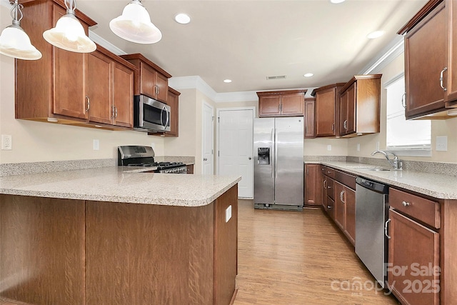 kitchen with kitchen peninsula, appliances with stainless steel finishes, pendant lighting, and sink