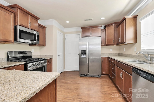 kitchen featuring light stone countertops, stainless steel appliances, crown molding, sink, and light hardwood / wood-style floors