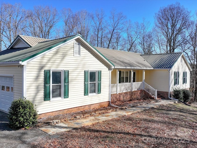 view of side of property with covered porch and a garage