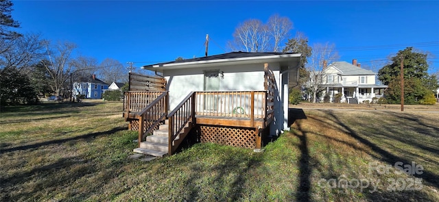 rear view of house featuring a lawn and a deck