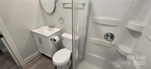 bathroom with a shower, hardwood / wood-style floors, vanity, and toilet