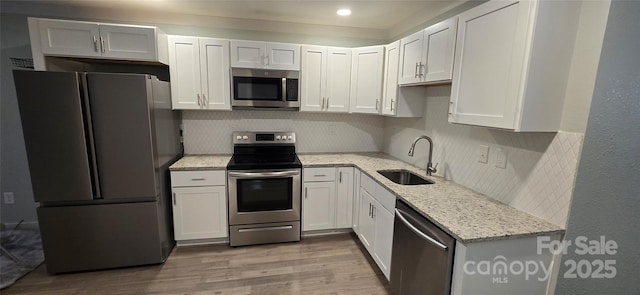 kitchen with light stone countertops, sink, stainless steel appliances, light hardwood / wood-style flooring, and white cabinets